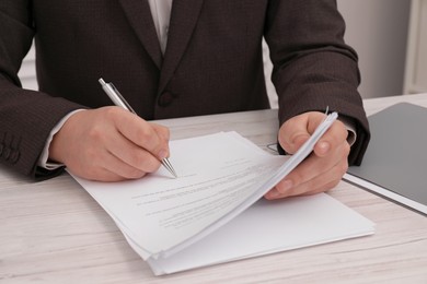 Photo of Man signing document at wooden table, closeup