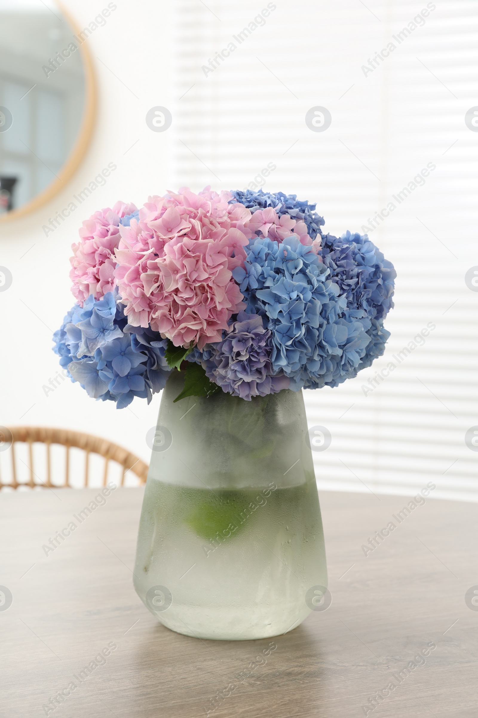 Photo of Vase with beautiful hydrangea flowers on wooden table indoors