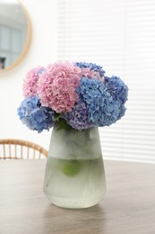 Photo of Vase with beautiful hydrangea flowers on wooden table indoors