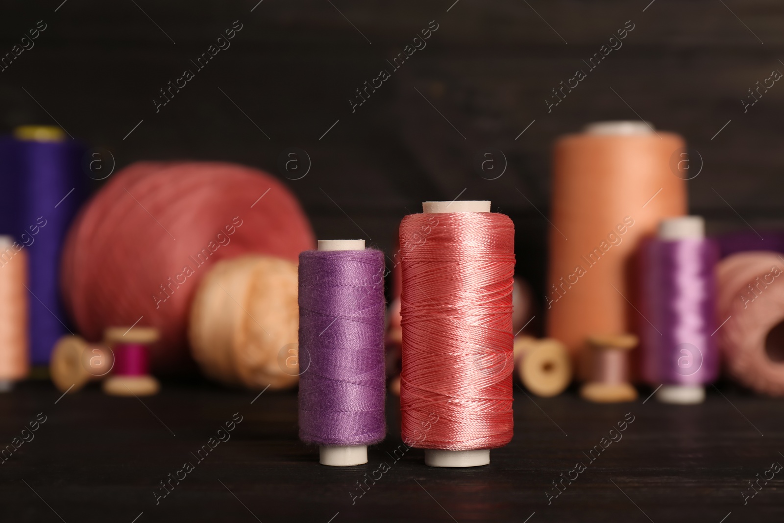 Photo of Different color sewing threads on black wooden table