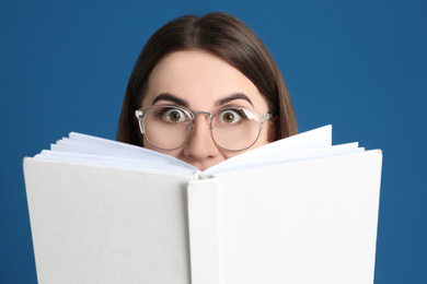 Young woman with book on blue background