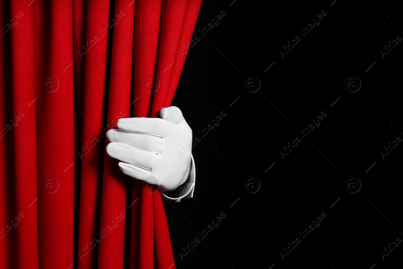 Photo of Person opening red front curtains on black background, closeup. Space for text