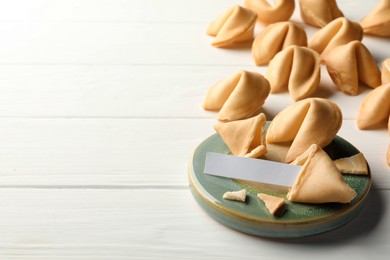 Photo of Tasty fortune cookies and paper with prediction on white wooden table, space for text