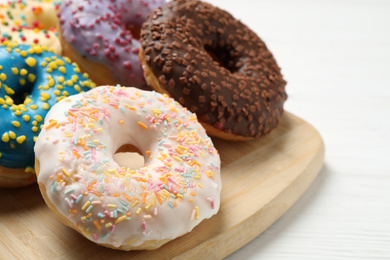 Photo of Yummy donuts with sprinkles on white wooden table, closeup