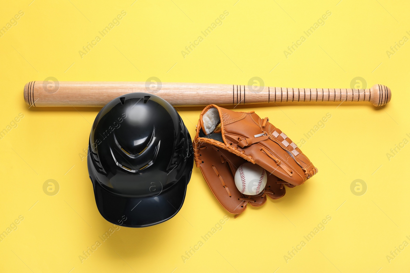 Photo of Baseball glove, bat, ball and batting helmet on yellow background, flat lay