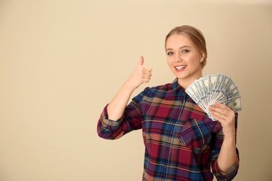 Portrait of happy young woman with money on color background. Space for text