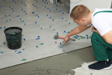 Man installing colorful wedges with plier on tiles indoors