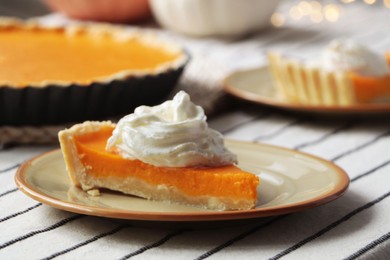 Photo of Piece of fresh homemade pumpkin pie with whipped cream on table