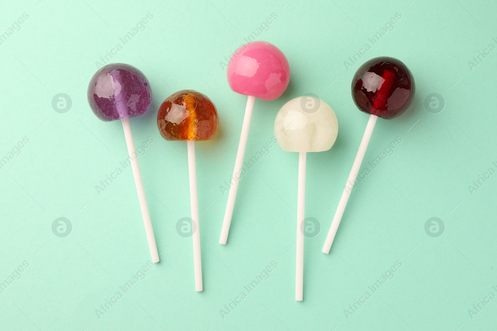 Photo of Tasty lollipops on turquoise background, flat lay