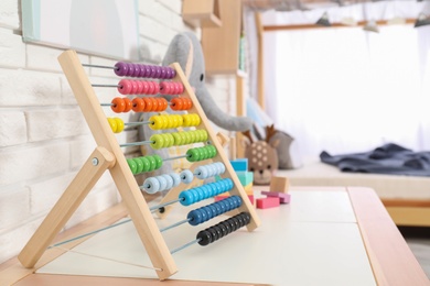 Photo of Colorful toy abacus on table in child's room. Space for text