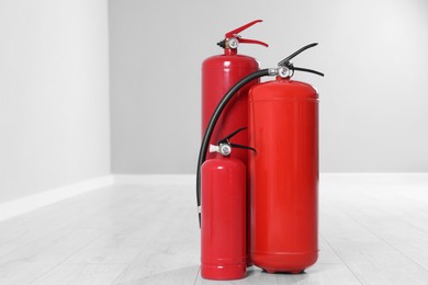 Photo of Fire extinguishers on floor indoors, space for text