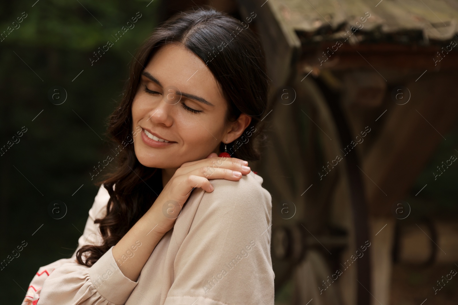 Photo of Beautiful woman near old wooden well in countryside, space for text