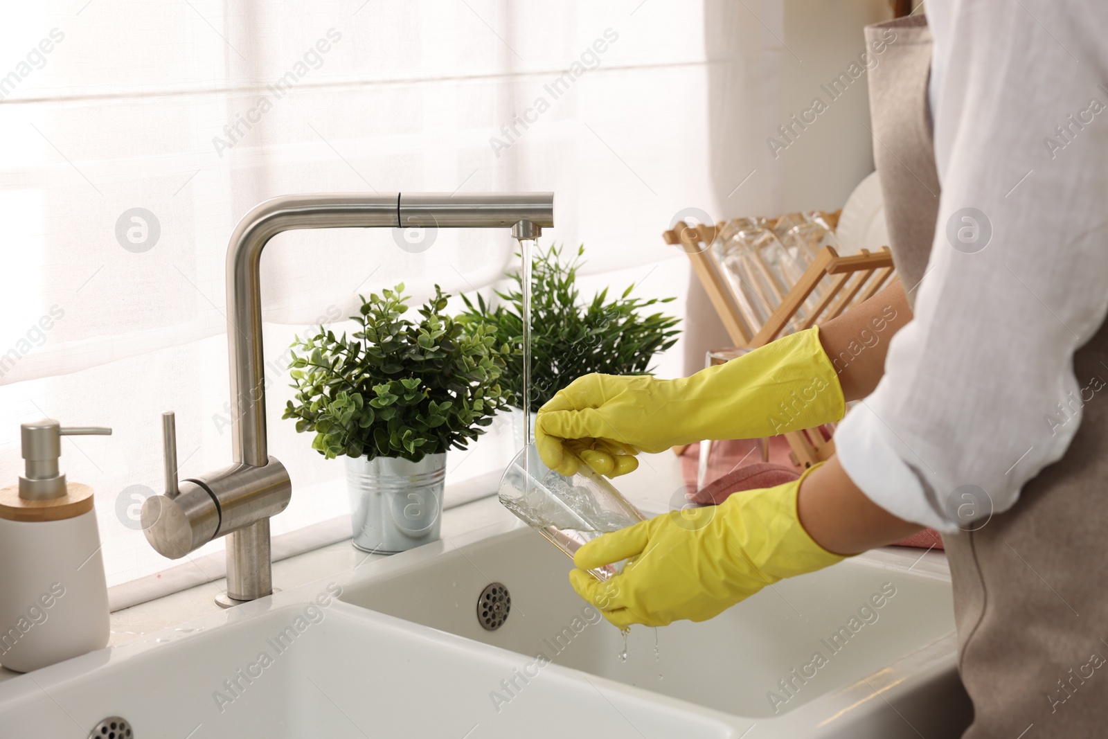 Photo of Woman washing glass at sink in kitchen, closeup