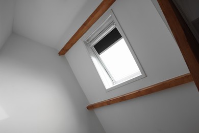 Photo of Roof window on slanted ceiling indoors, low angle view