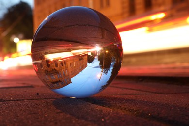 Beautiful city street, overturned reflection. Crystal ball on asphalt road at night, closeup