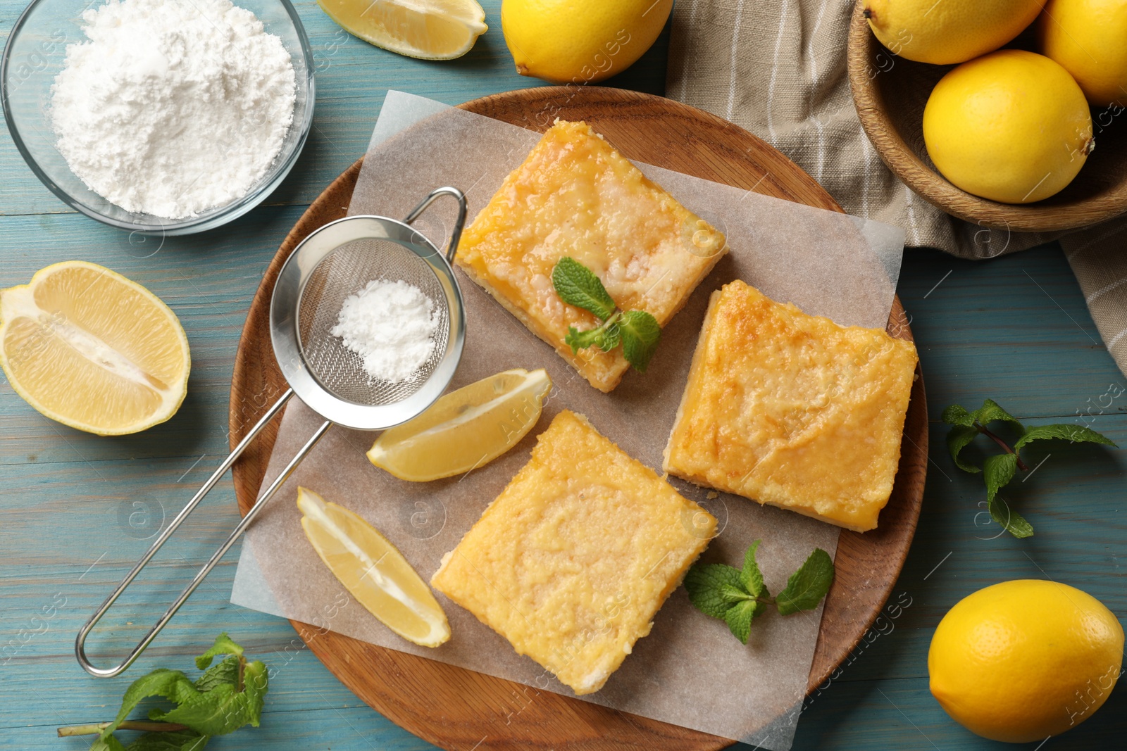 Photo of Tasty lemon bars and mint on light blue wooden table, flat lay