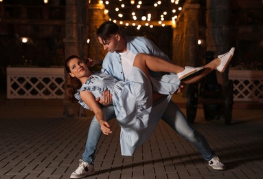 Photo of Beautiful young couple practicing dance moves in evening outdoors