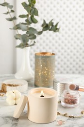 Composition with burning soy candle on white marble table