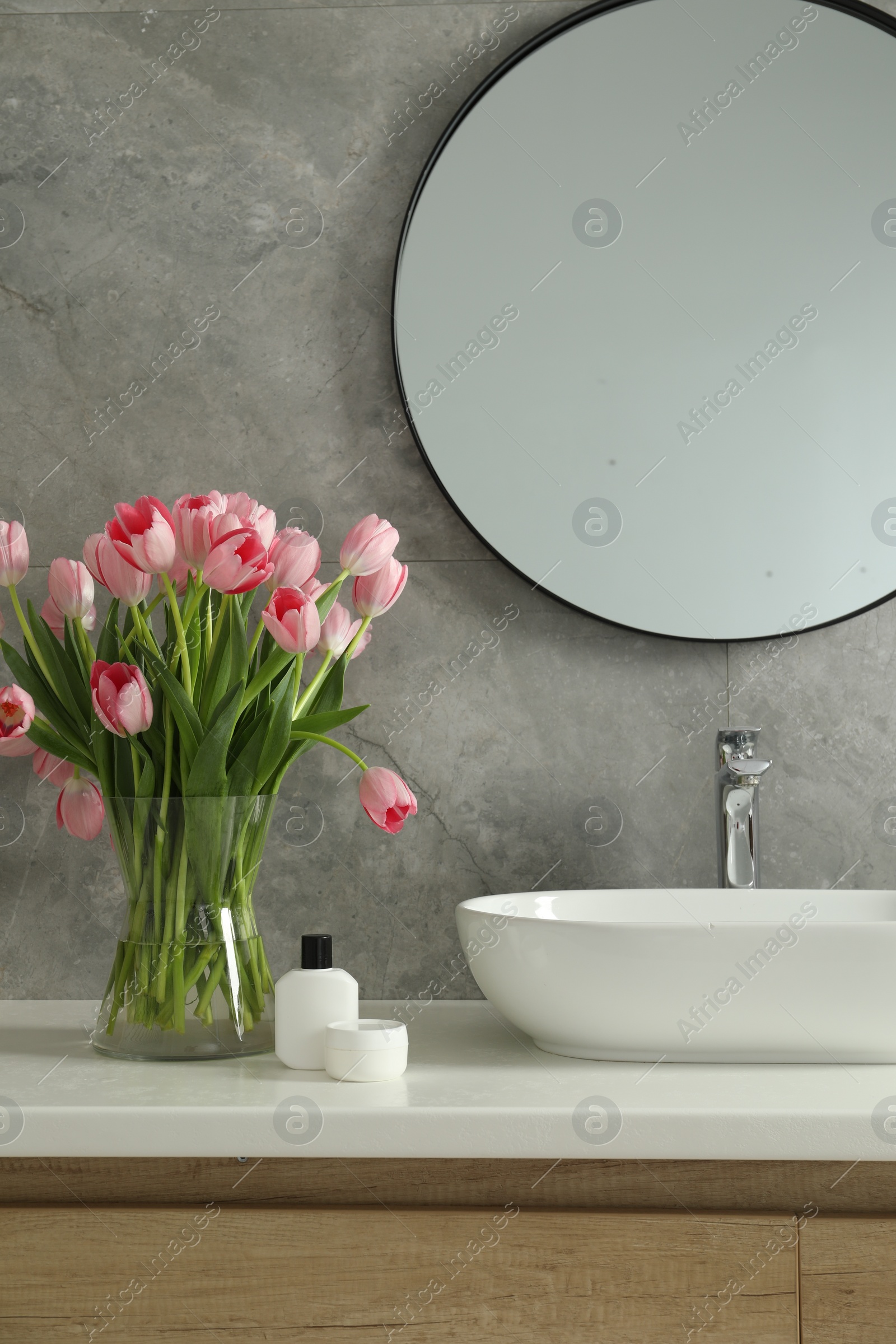 Photo of Vase with beautiful pink tulips near sink in bathroom