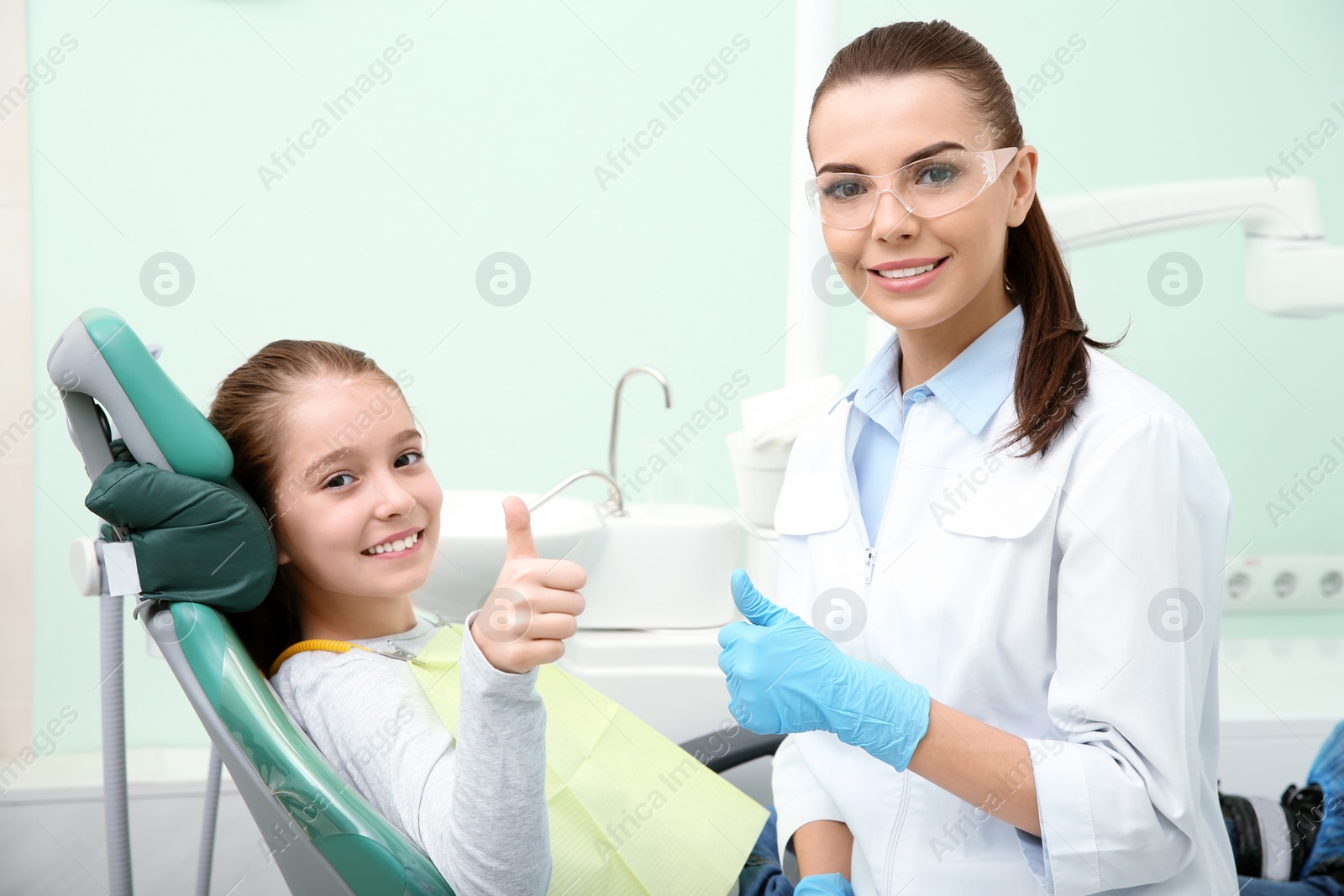 Photo of Professional dentist and happy little patient in modern clinic