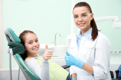 Professional dentist and happy little patient in modern clinic