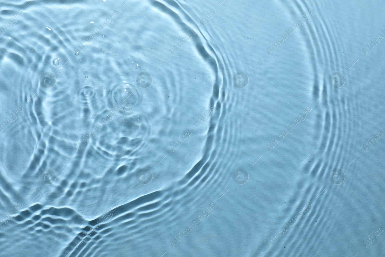 Photo of Rippled surface of clear water on light blue background, top view