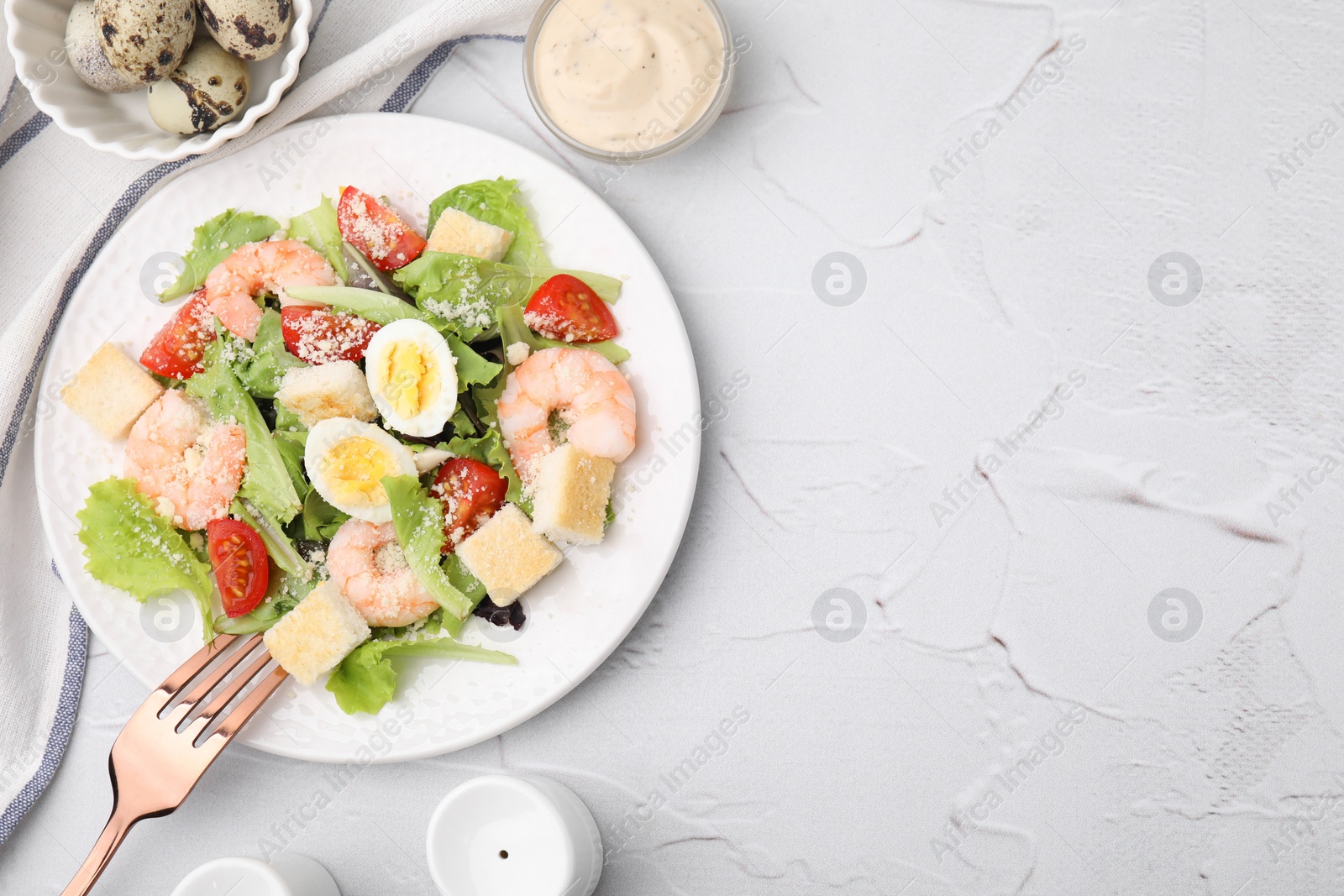 Photo of Delicious Caesar salad with shrimps and fork served on white textured table, flat lay. Space for text