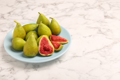 Cut and whole green figs on white marble table, space for text