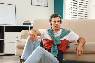 Photo of Man listening to audiobook near sofa at home