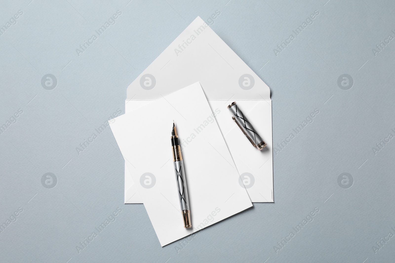 Photo of Blank sheet of paper, letter envelope and pen on grey background, top view