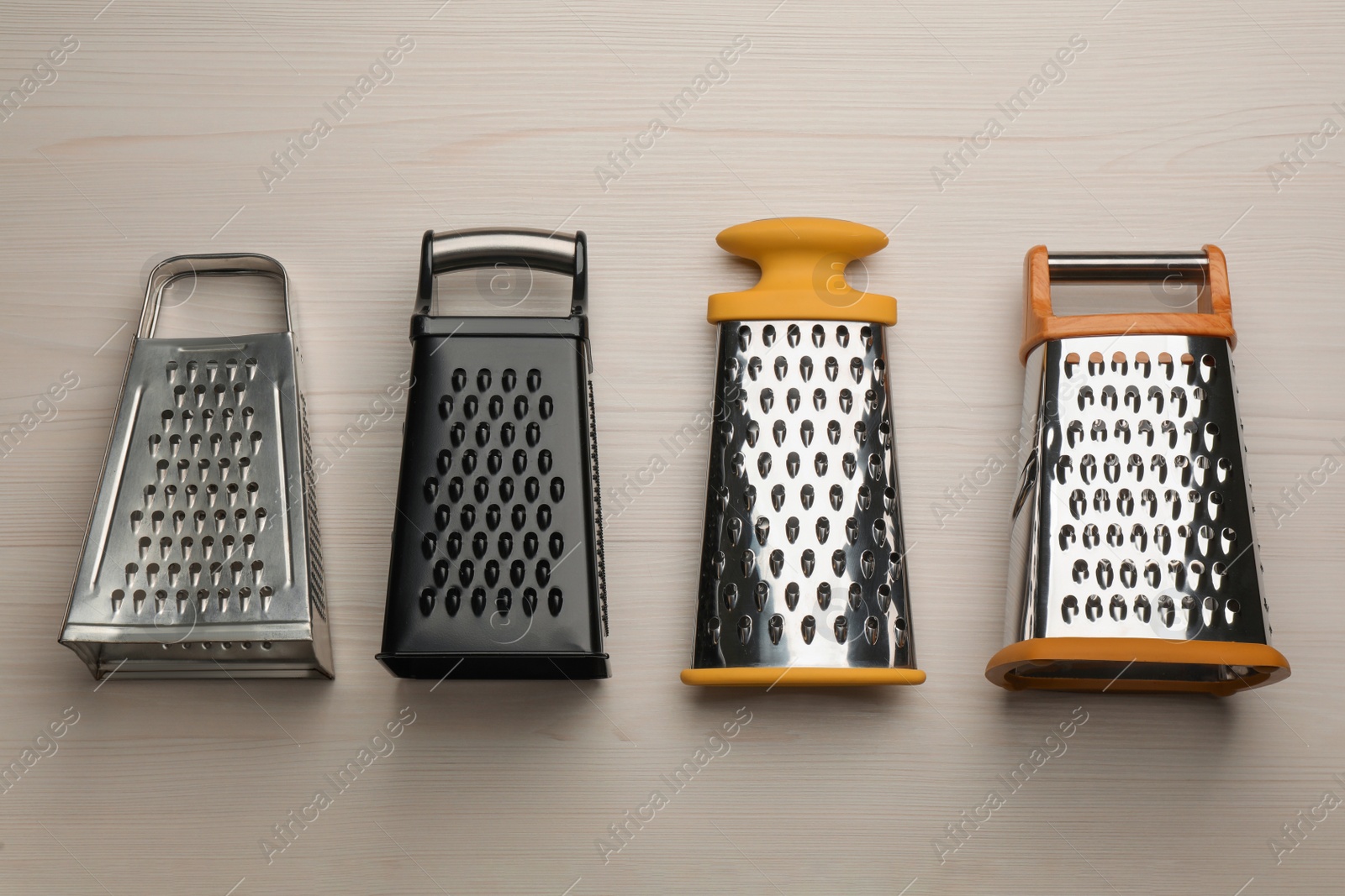 Photo of Different modern graters on white wooden table, flat lay