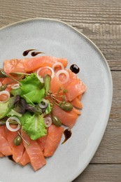 Delicious salmon carpaccio served on wooden table, top view