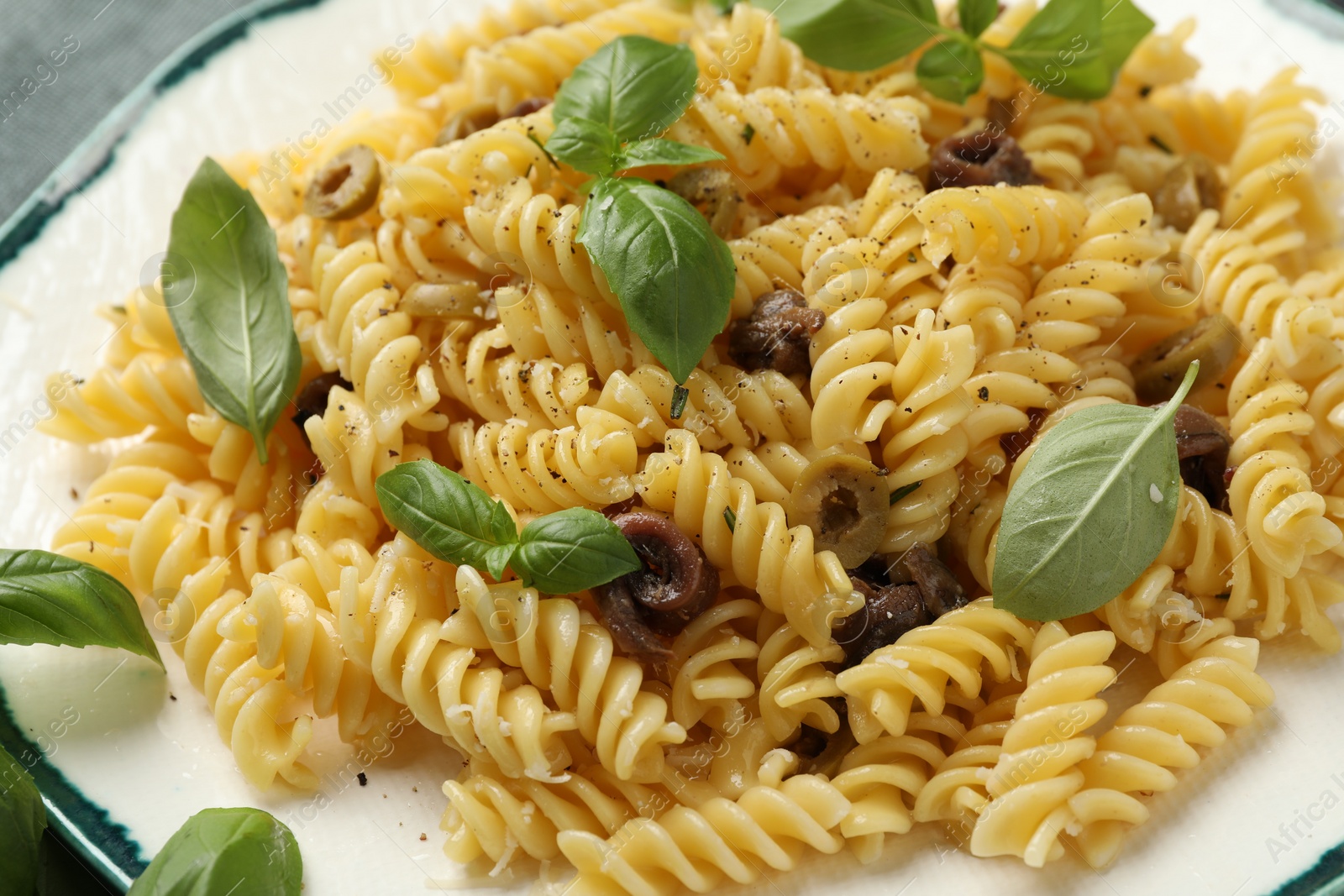 Photo of Plate of delicious pasta with anchovies and basil on table, closeup