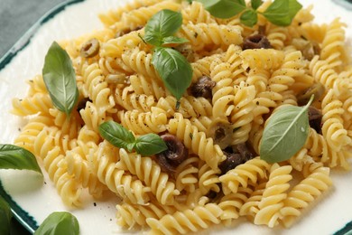 Plate of delicious pasta with anchovies and basil on table, closeup