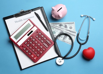 Flat lay composition with health insurance form, calculator and stethoscope on blue background