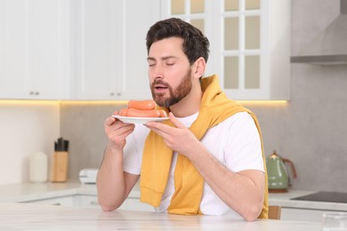 Photo of Man enjoying sausages at table in kitchen
