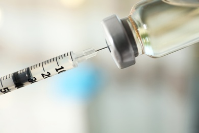 Filling syringe with vaccine on blurred background, closeup