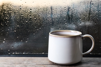 Cup of hot tea on wooden window sill. space for text. Rainy weather