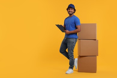 Happy courier with clipboard and stack of parcels on orange background, space for text