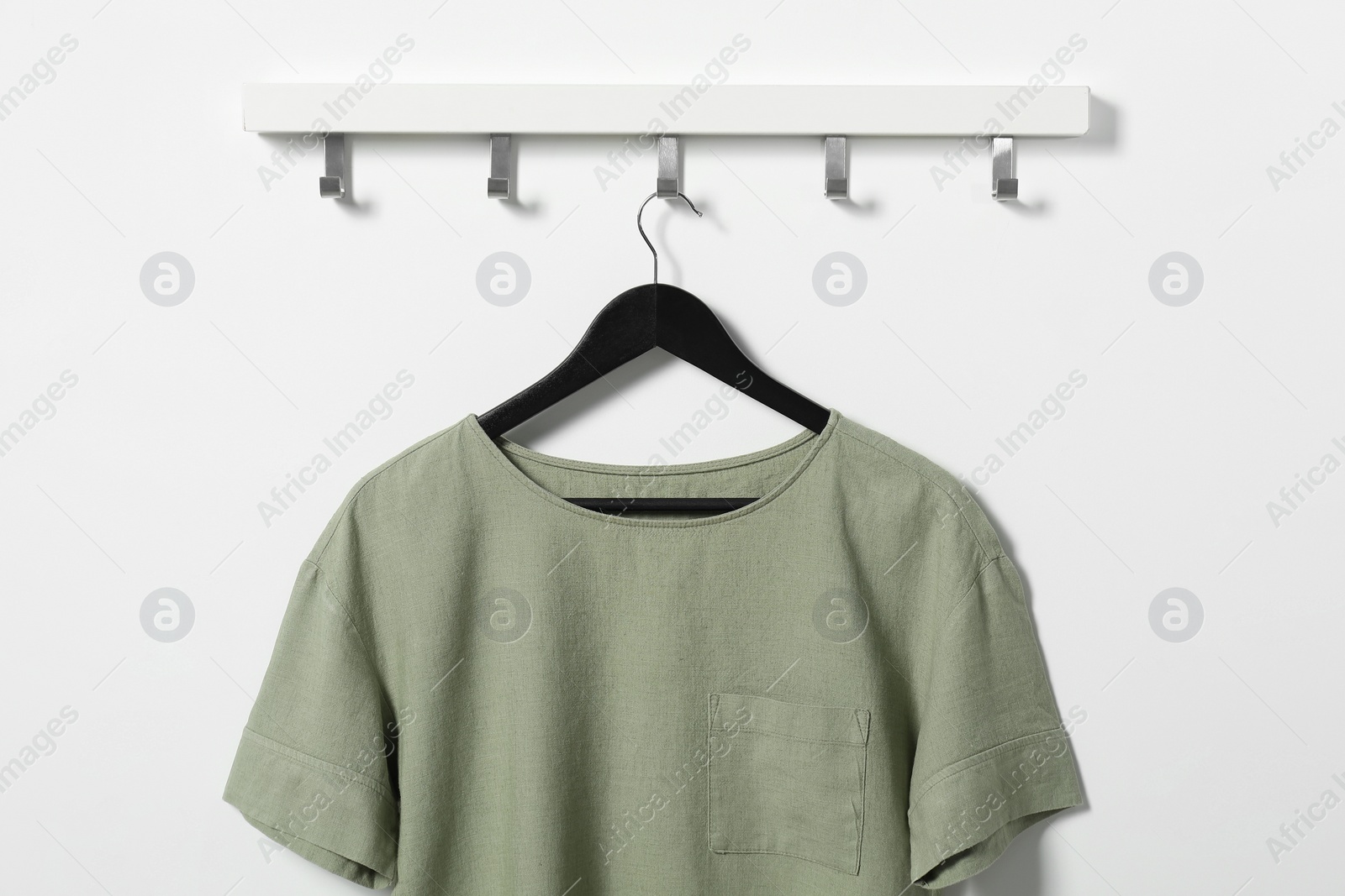 Photo of Hanger with olive t-shirt on white wall