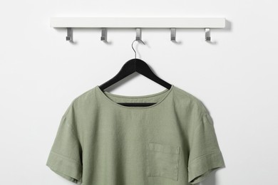 Photo of Hanger with olive t-shirt on white wall