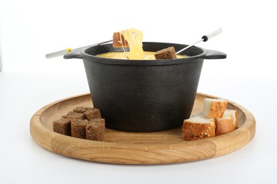 Photo of Fondue with tasty melted cheese, forks and pieces of bread isolated on white