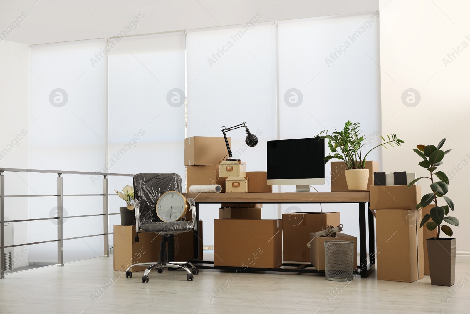 Photo of Cardboard boxes, computer and furniture in new office. Moving day