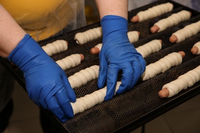 Photo of Baker putting sausage rolls on tray in workshop, closeup