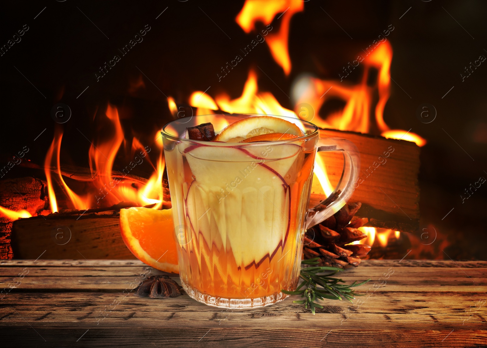 Image of Mulled wine in glass cup on wooden table near fireplace