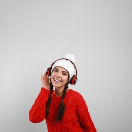 Photo of Young woman listening to music with headphones on grey background