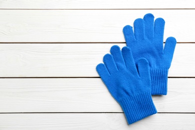 Stylish blue gloves on white wooden background, flat lay. Space for text