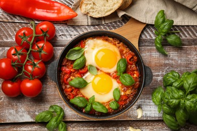 Photo of Delicious Shakshuka served on wooden table, flat lay