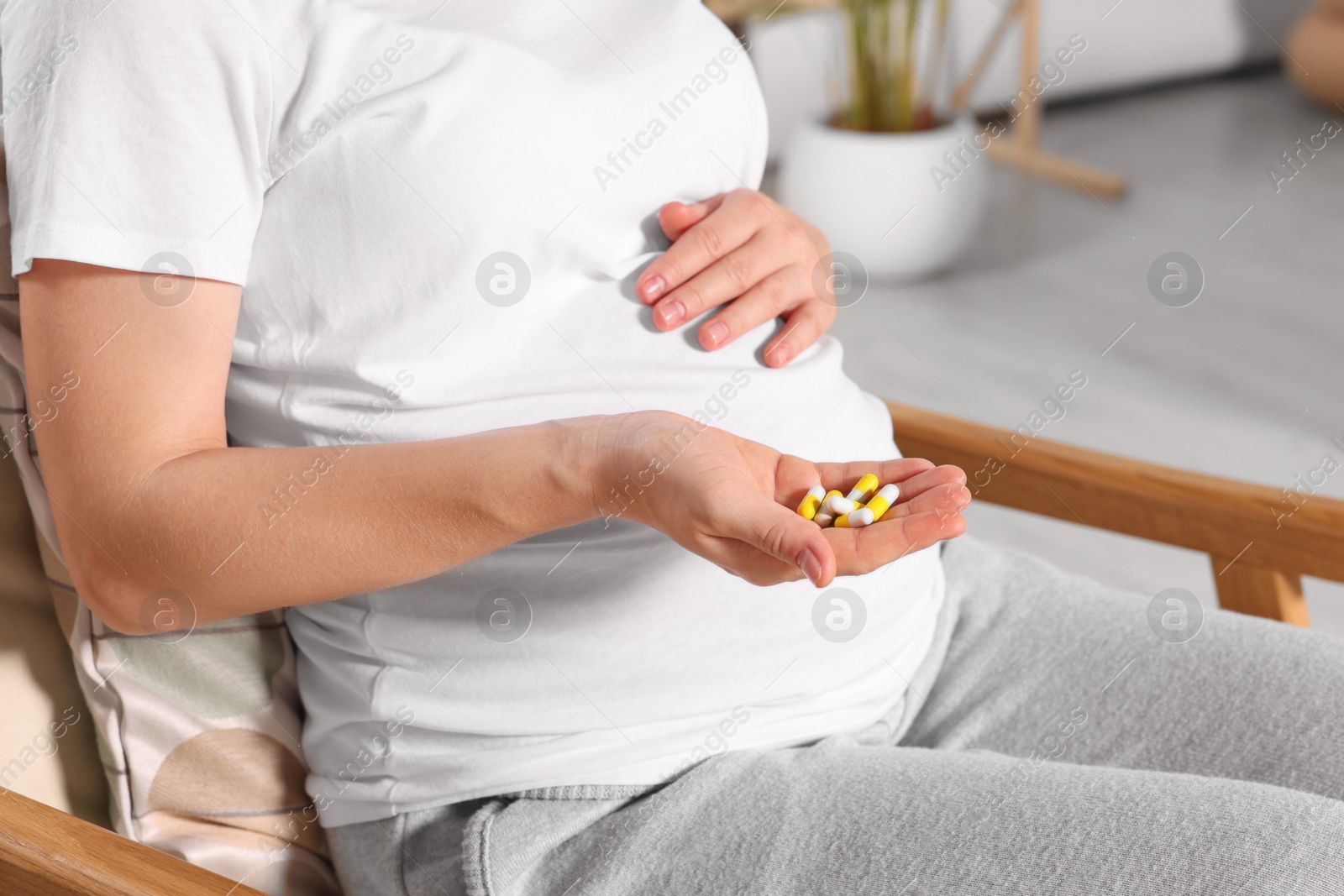 Photo of Pregnant woman taking pills at home, closeup