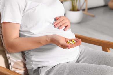 Pregnant woman taking pills at home, closeup